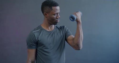 Porträt eines muskulösen afroamerikanischen Mannes, der mit Hanteln trainiert und sich auf Gewichtheben konzentriert
