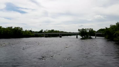 Zumbido volando a lo largo del puente con coches que cruzan el poderoso río que fluye rápidamente en Chippewa Fal