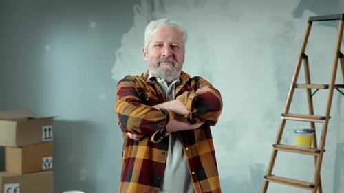 Elderly Gray Haired Man with Beard Looking at Camera Crossing Arms Over His Chest and Smiling