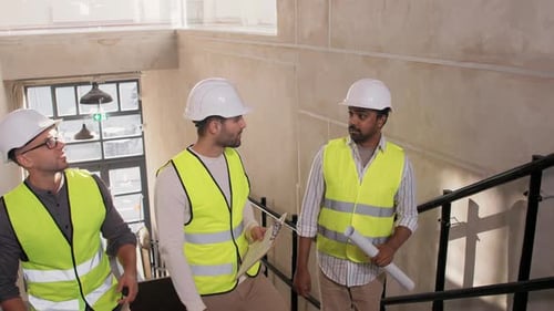 Architekten mit Bauplänen gehen die Treppe hinauf und besprechen gemeinsam Baupläne