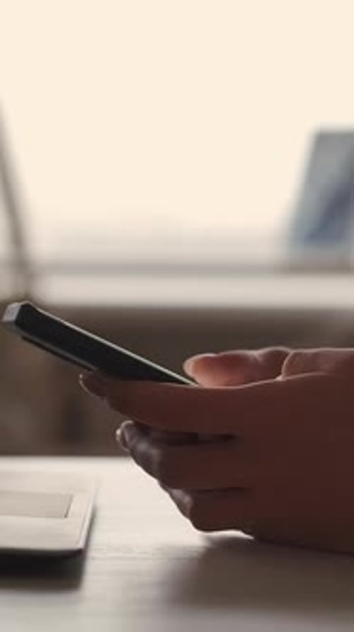 Hands Using Mobile Phone with Computer in Background