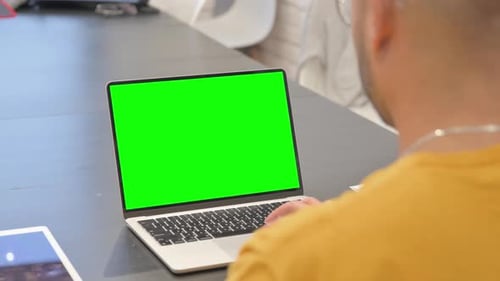 Hispanic Man Working on Laptop with Green Screen