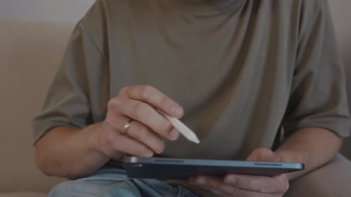 Man Uses Stylus on Tablet Indoors Close Up