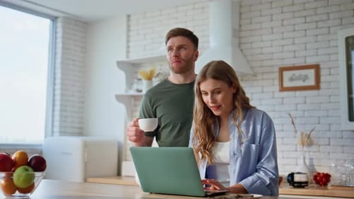 Couple working on laptop in kitchen at home