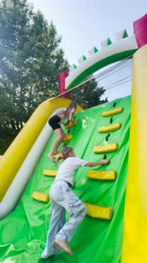 Children Climb Inflatable Rock Wall on Sunny Day