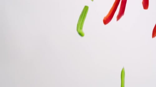 Colorful Sliced Bell Peppers Falling on White Background