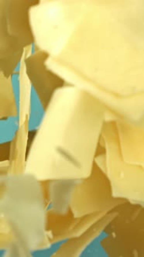 Parmesan Cheese Flies Up and Falls Down on a Blue Background Filmed on a Highspeed Camera at 1000