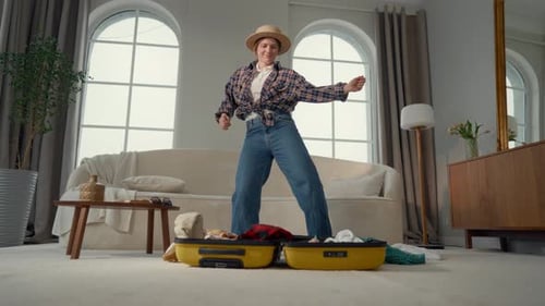 Woman Dancing While Packing Suitcase for Vacation
