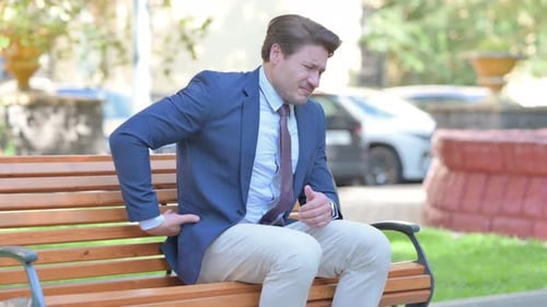 Man in Suit Experiences Back Pain on Bench