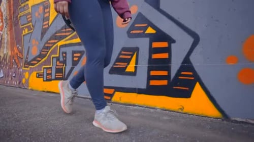 Mulher caminhando ao lado de uma parede de grafite colorida e vibrante. Foto em câmera lenta em close-up
.