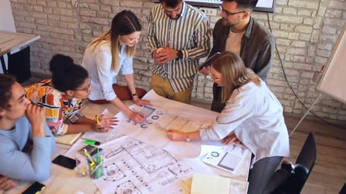 Group of young business people discussing architectural designs in office.