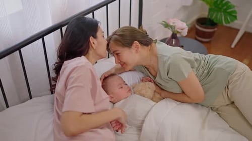 Loving Women Watch Over Sleeping Baby in Bed