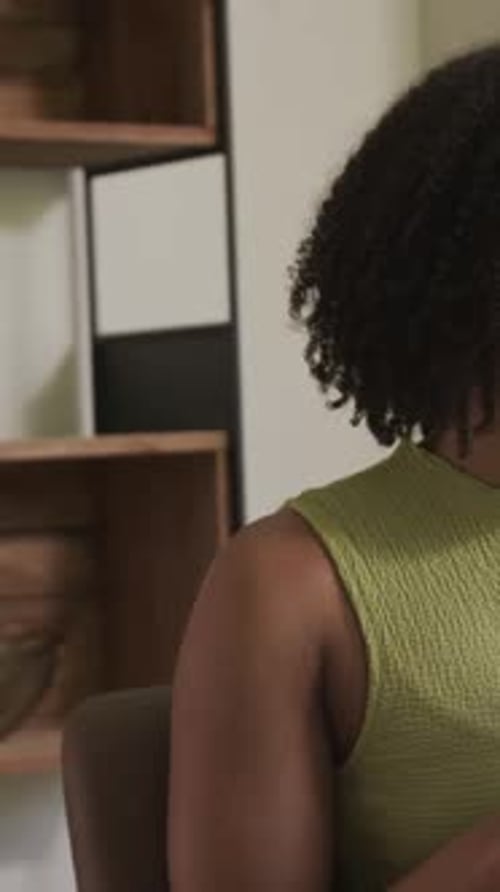 Vertical video: Gesturing host in green top near laptop at desk as camera showing mic for recording