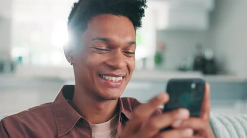Young Adult Smiling While Using Smartphone Indoors