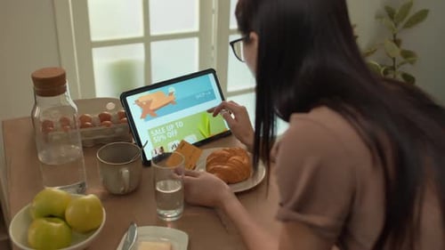 Woman Shopping Online with Tablet at Breakfast Table