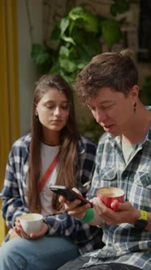 Couple Looks at Phone Together in Urban Cafe