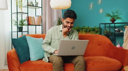 Young Adult Celebrating Good News on Laptop at Home