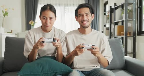 Smiling Couple Plays Video Games Together on Sofa