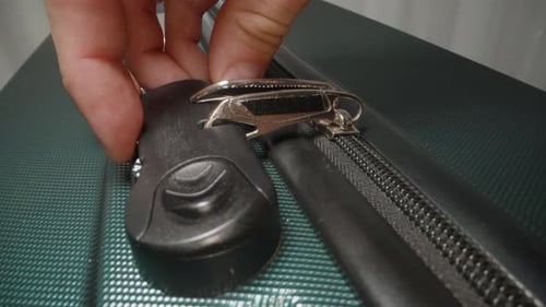 A Hand carefully selects the correct combination on the lock, preparing to unzip and open.
