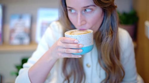 Woman drinking latte art coffee from ceramic cup in a cafe