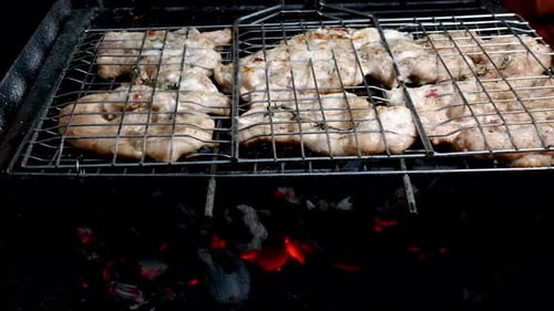 Pieces of Juicy Chicken Fillet Fried on Burning Charcoal on Grill Grate Turning