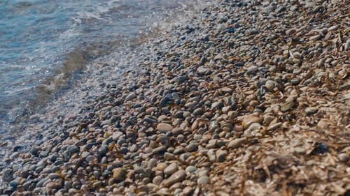 Waves of a Mediterranean pebble beach with turquoise water