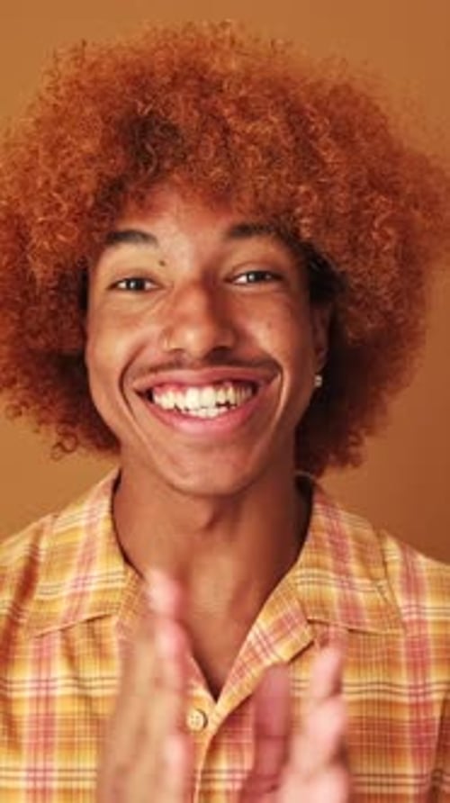 Guy is emotionally telling something and looking at camera isolated on brown background in studio