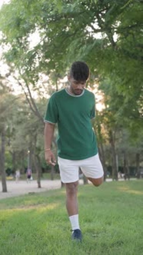 Afro Young Man in Sportswear Warming Up Before Exercising Outdoors in a Park