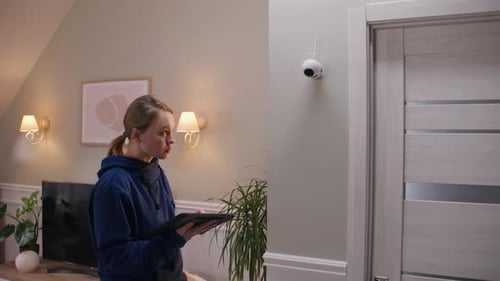 Frau richtet CCTV-Kamera mit Tablet ein