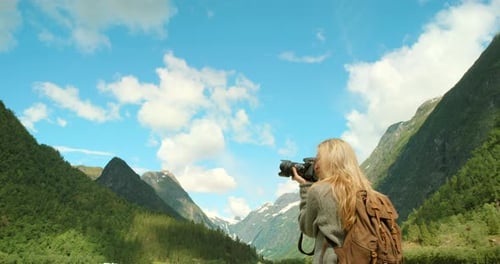 Woman, tourist and camera for pictures, mountain and norway with backpack and photography