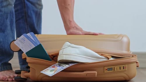 Nahaufnahme von Reisehänden, die auf eine platzende Gepäcktasche drücken