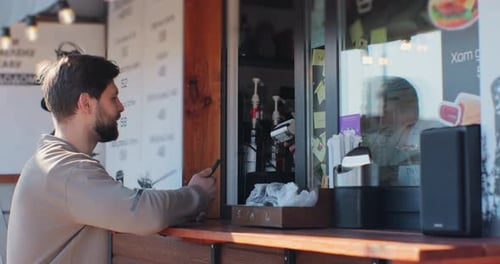 Man Pays with Phone at Outdoor Food Vendor