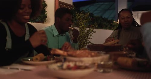 Happy african family having fun eating dinner together at home terrace - Home moments