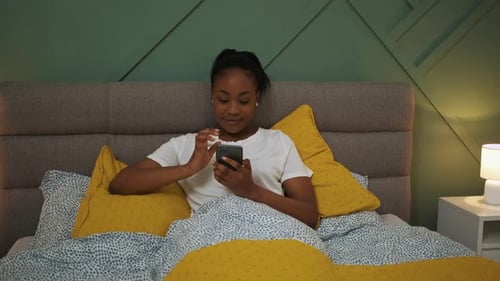 Woman Smiles Using Phone in Bed at Night