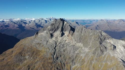 Aerial flying toward a rocky peak in New Zealand's Southern Alps mountains.