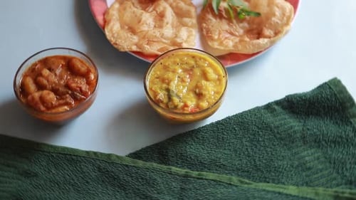 rotation Chole Bhature or Chick pea curry and Fried Puri served in terracotta crockery over blue bac