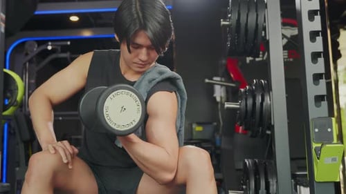 Man Working Out Biceps With Dumbbell at Gym