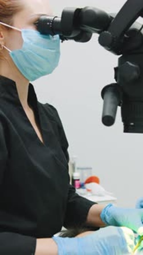 Der Zahnarzt verwendet das Mikroskop zur zahnärztlichen Behandlung während der Patientenuntersuchung in einer Klinik an einem geschäftigen Ort