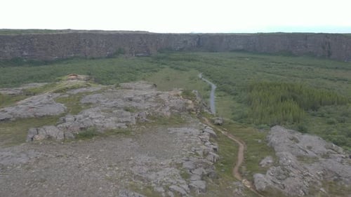 Flying past point of Eyjan cliff rock formation looking at horseshoe shape valley in Iceland