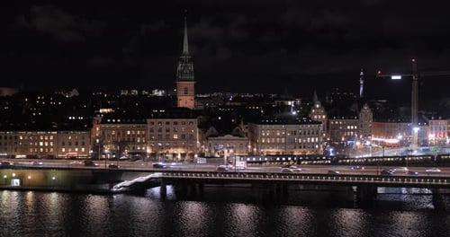Traffic Driving In The Road Passing By Illuminated Building At Night In Stockholm, Sweden. - wide pa