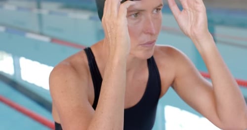 Caucasian female swimmer athlete adjusts her swimming goggles at the pool