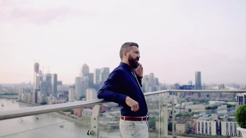 A Portrait of Businessman with Smartphone Standing Against London View Panorama