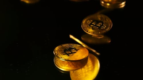 Golden Bitcoin Coins Falling on a Black Surface