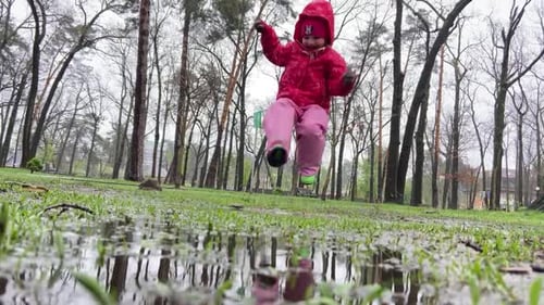 Child Splashing in Puddles in Spring Park