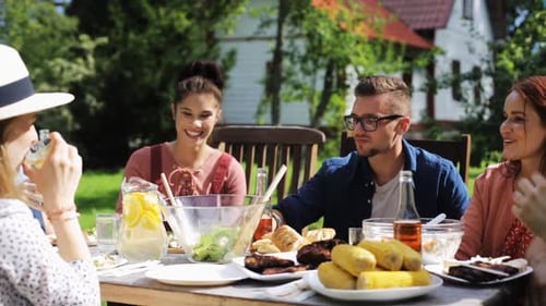 Happy friends enjoying delicious food and drinks at summer garden party