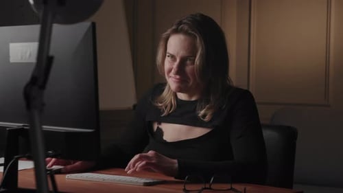 In a Modern Office Setting a Smiling Woman is Focused on Working on a Computer