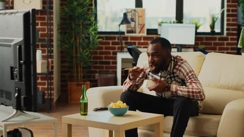 Man Eating Noodles on Sofa at Home