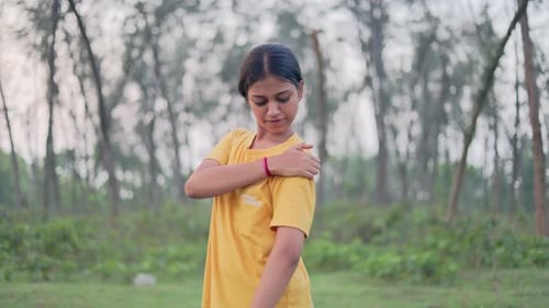 Teen girl massaging her shoulder in outdoor setting