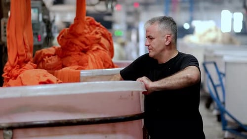 Man Working in Textile Factory with Orange Fabric