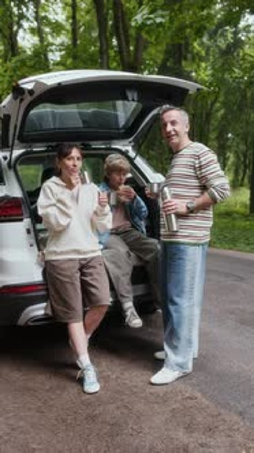 Family Having Drinks Near Car in Woods